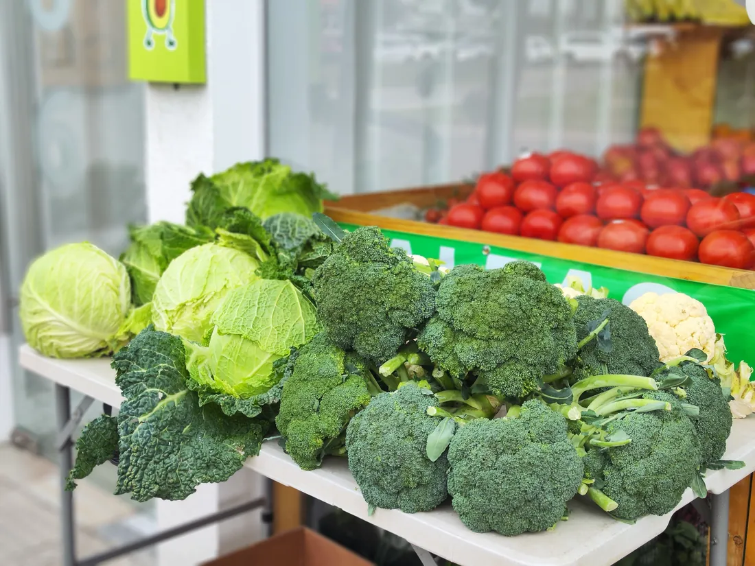 Verduras frescas exhibidas en el local de Hasspal, con el letrero de la marca de fondo